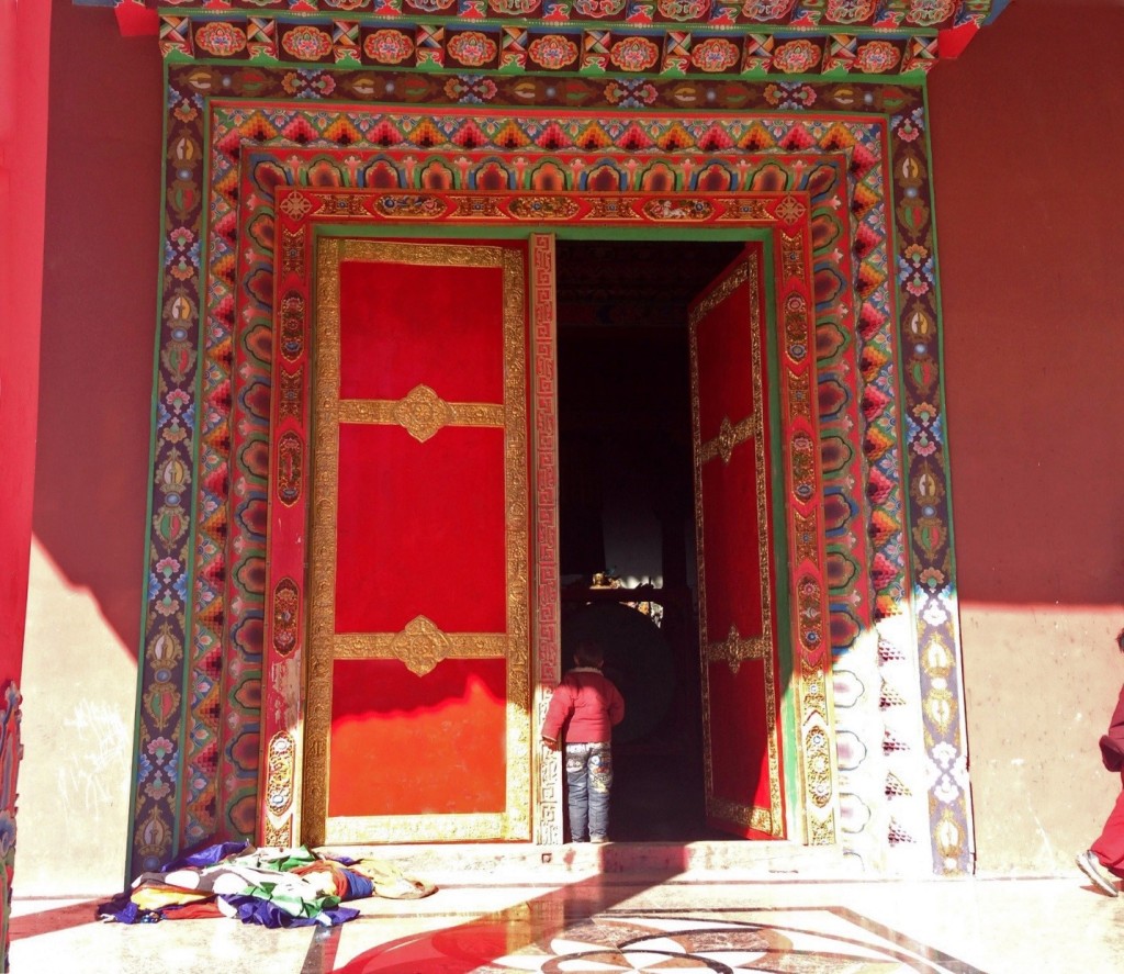 Child peering through the main door of the Surmang Shedra